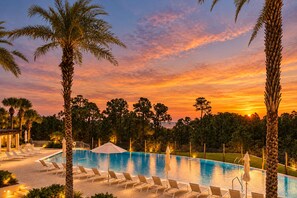 A swimming pool with lounge chairs and umbrellas, surrounded by palm trees and a sunset sky. - Stunning 30A Home-Pool, Bikes, Golf Cart, Pickleball, AC, 5 mins to the Beach (Santa Rosa Beach)