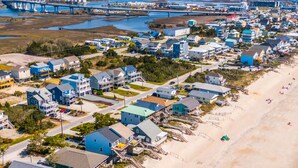 An aerial view of a coastal town with beachfront properties, a bridge, and industrial facilities in the background. - Keeping It Salty #101 Oceanfront Duplex, Private Beach Access, Dogs Allowed! (Surf City)