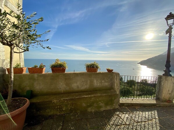 A balcony with terracotta pots and a view of the sea.