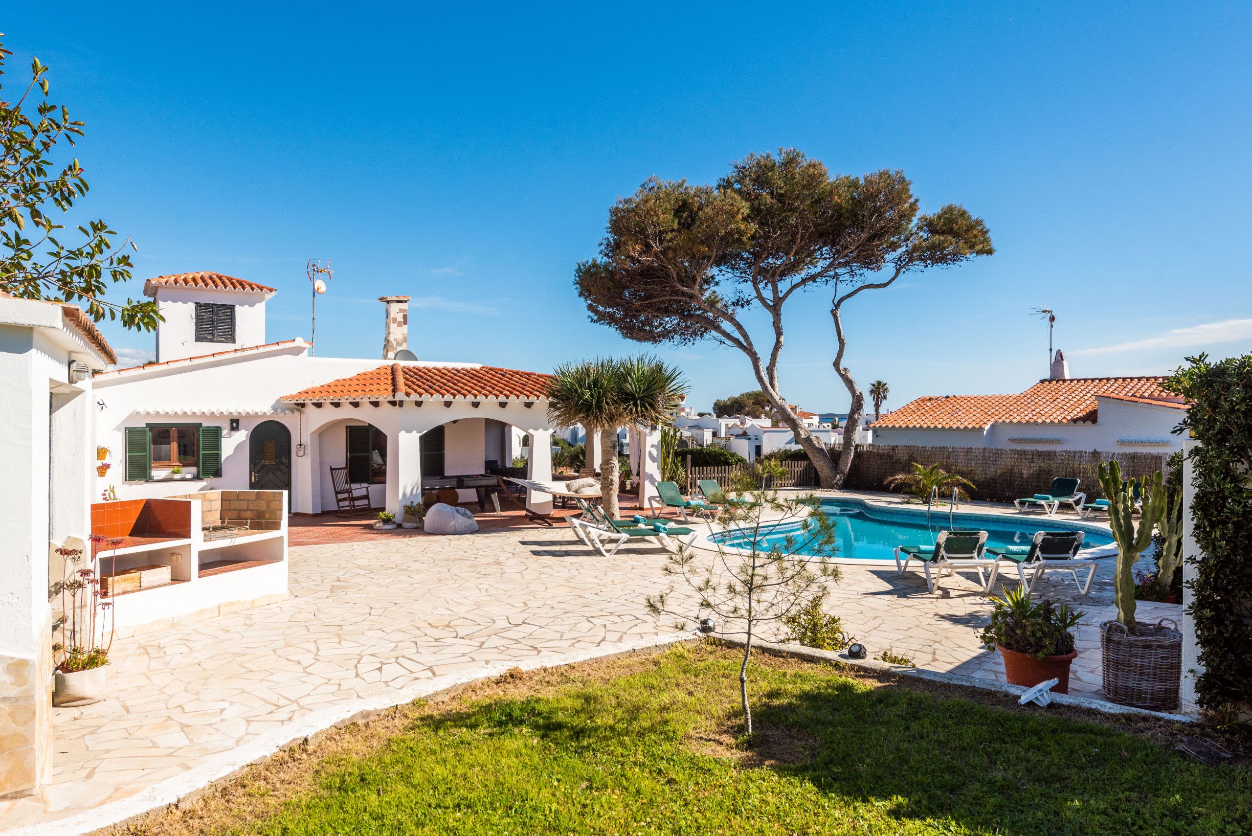 A villa with a swimming pool, outdoor seating, and a garden.