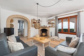Ein Wohnzimmer mit Kamin, Sofas, einem Couchtisch und Regalen mit Dekoration.