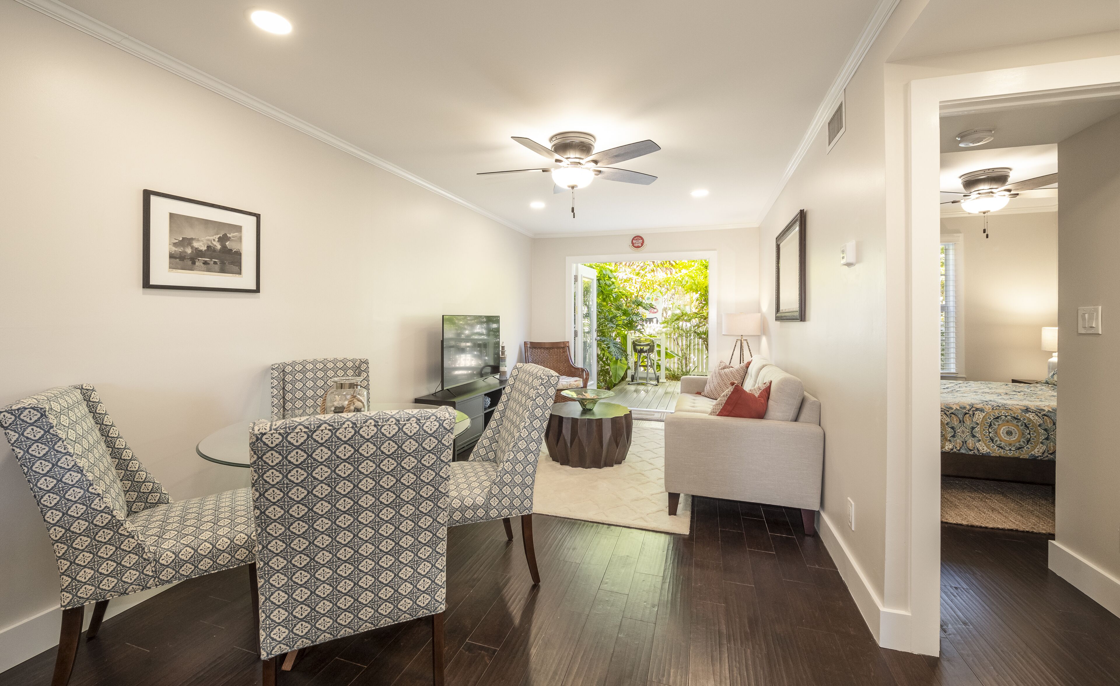 A modern living room with patterned chairs, a sofa, and a ceiling fan.