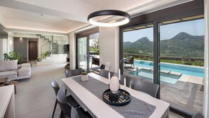 Una sala de estar moderna con comedor, ventanas grandes y vistas a montañas.