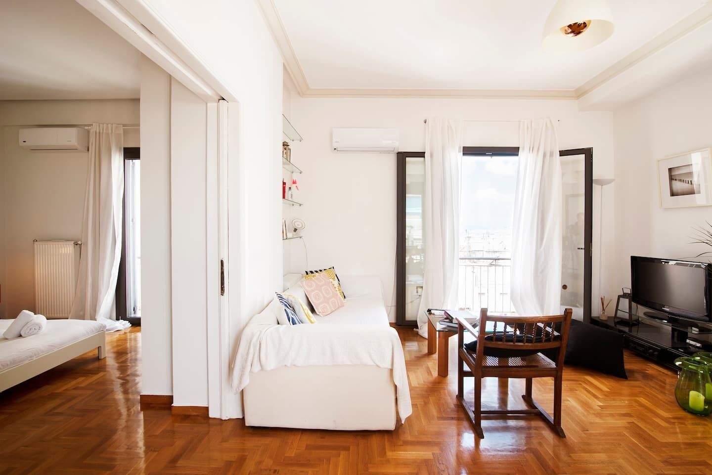 Een moderne hotelkamer met een bed, een zithoek met een stoel, een televisie en een balkon met uitzicht.