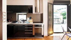 Une cuisine moderne avec des meubles noirs, une hotte en acier inoxydable et un four encastré.