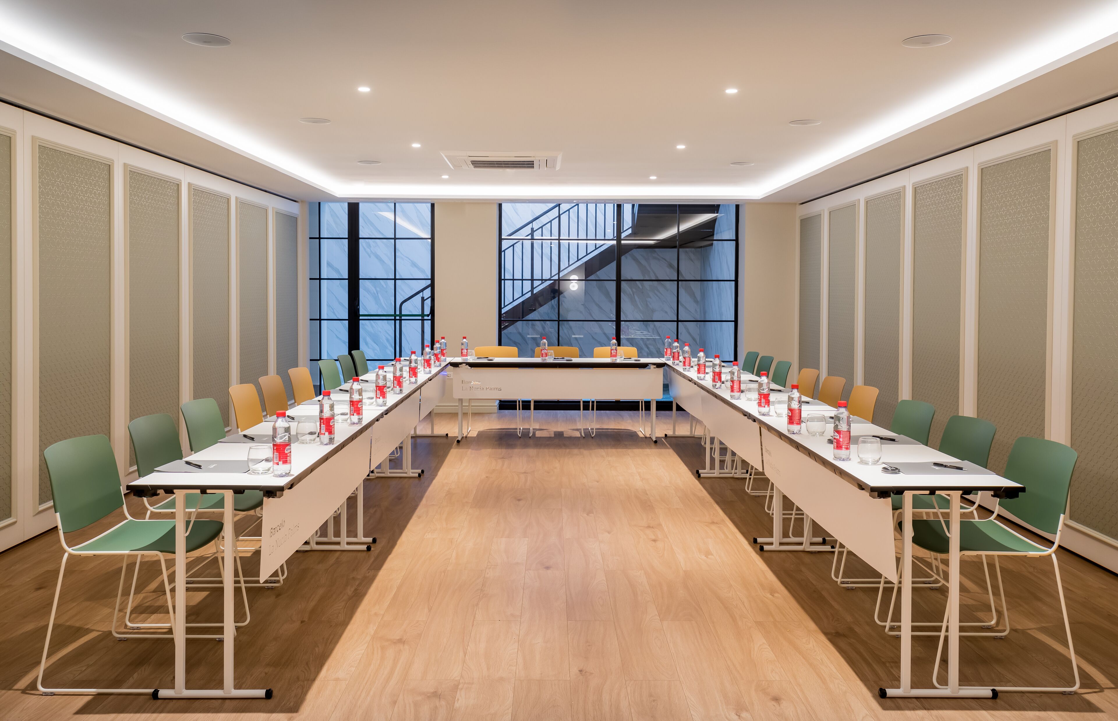 Un salón de conferencias con una larga mesa, sillas y botellas de agua.