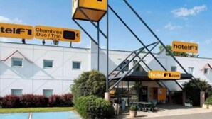 A hotel with multiple signs indicating 'hotel FT' and 'hotel F1.com'. There are outdoor seating areas and a pool visible. - Premiere Classe Arras - Tilloy Les Mofflaines (Tilloy-Les-Mofflaines)