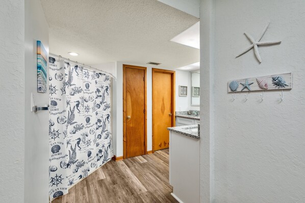 Un couloir avec une porte en bois, un mur blanc orné d’une étoile de mer et un plancher en bois.