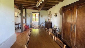 A wooden dining room with a long table and chairs, a wooden cabinet, and a large wooden door.