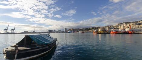 A harbor with a boat docked in the foreground, a cityscape in the background, and a clear sky.