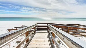 Une promenade en bois qui mène à une plage, avec un ciel dégagé.