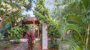 Ein Garten mit einer Holz-Pergola, verschiedenen Pflanzen und einem Kiesweg.