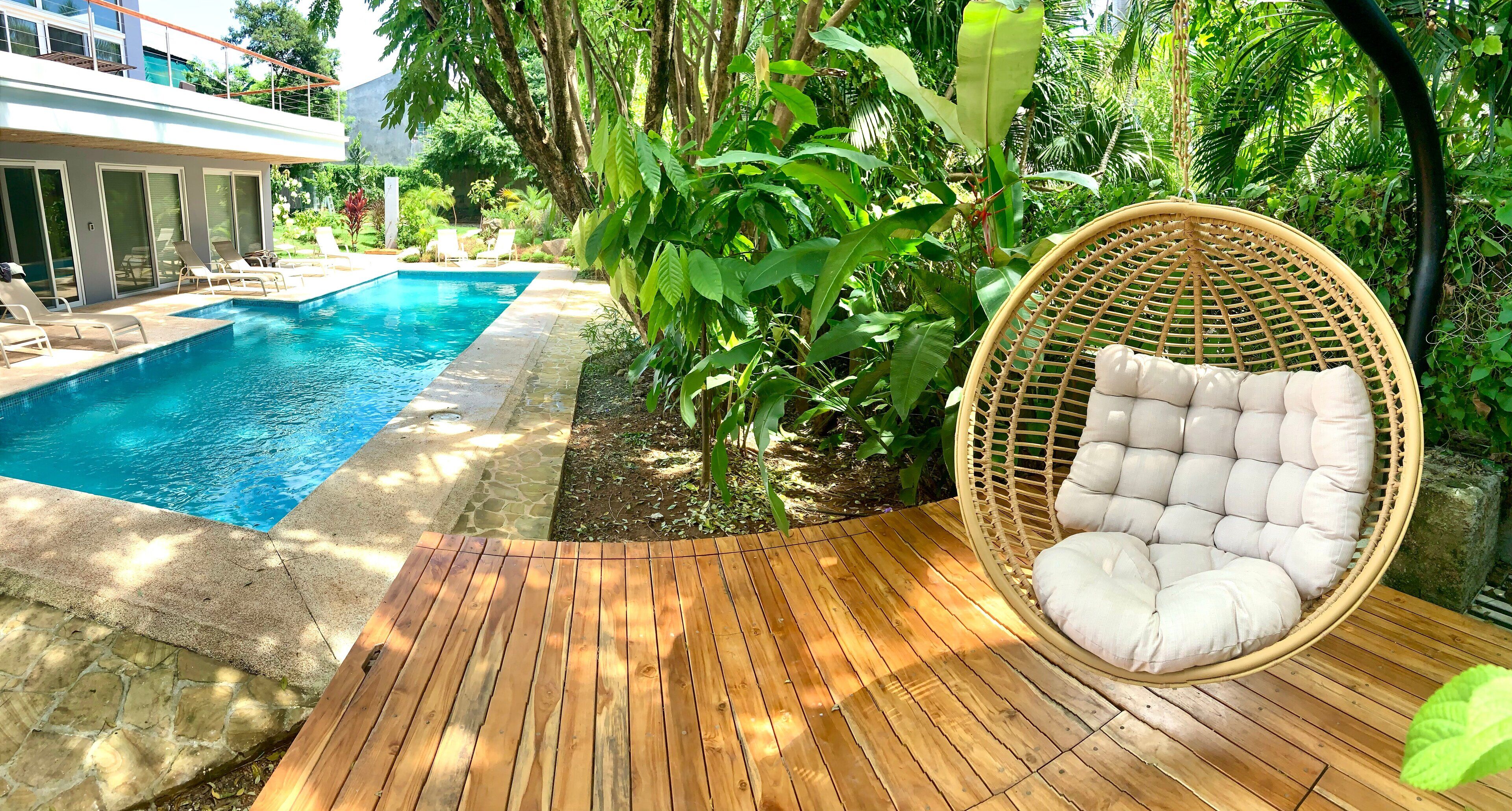 A wooden deck with a wicker chair and a pool.