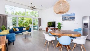 Ein modernes Wohnzimmer mit einem großen Fernseher, einem Holzessttisch und einem blauen Sofa.