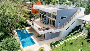 Ein modernes Haus mit Pool, Sitzgelegenheit im Freien und einem Garten.