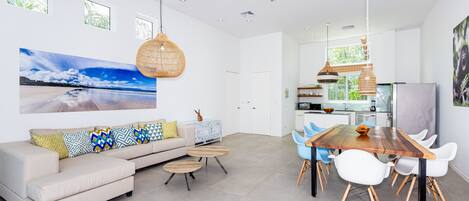 Un salon spacieux comprenant un canapé, une table basse et un coin repas avec des chaises et une table en bois.