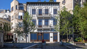 Un edifici de diverses plantes amb grans finestres i un balcó.