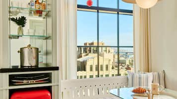 Una cocina moderna con un refrigerador rojo, una mesa de vidrio y un banco con cojines a rayas.