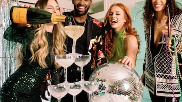 A group of people at a party with a table set with champagne glasses and a disco ball.