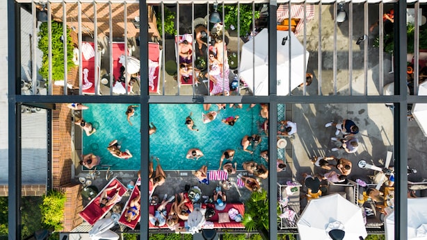 A rooftop pool area with multiple swimming pools and sun loungers.