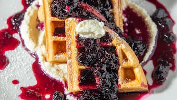Une assiette de gaufres garnies de myrtilles et de crème fouettée.