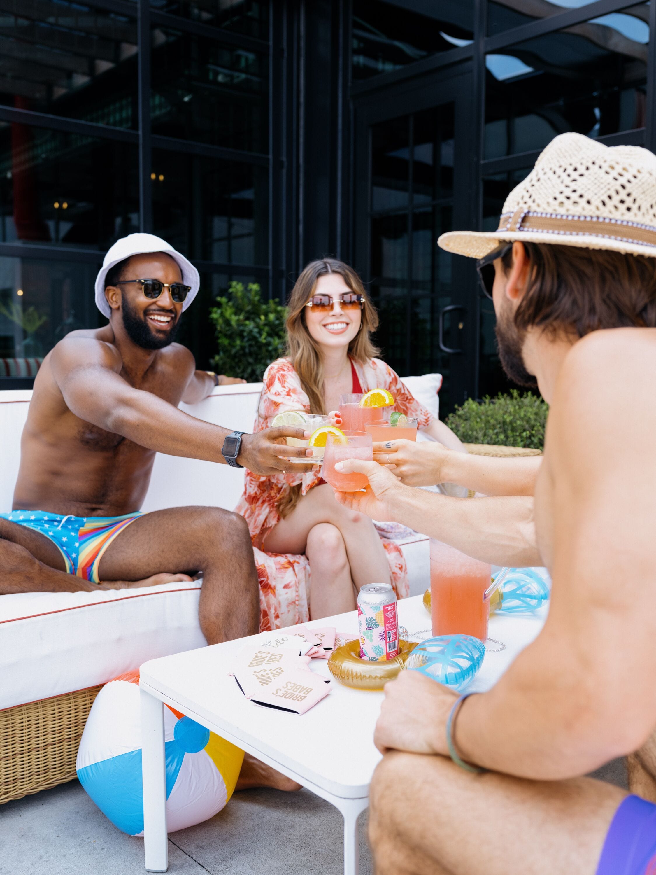 A group of people sitting on a white outdoor sofa with a wicker table in front.