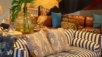 Una sala acogedora con un sofá estampado, una mesa de centro de madera y un jarrón decorativo con una planta.
