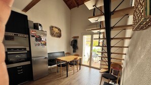 A kitchen with a wooden table and chairs, a refrigerator, and a staircase leading to a balcony. - Familienurlaub, Haustiere, Sonne, Meer, Wandern, Radfahren (Argelès-sur-Mer)
