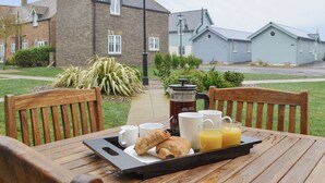 A breakfast tray on a wooden table with croissants, coffee cups, and orange juice.