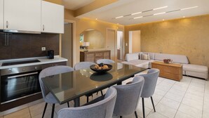 A modern kitchen with built-in appliances, a dining area with a glass table and chairs, and a living area with a sofa and a coffee table.