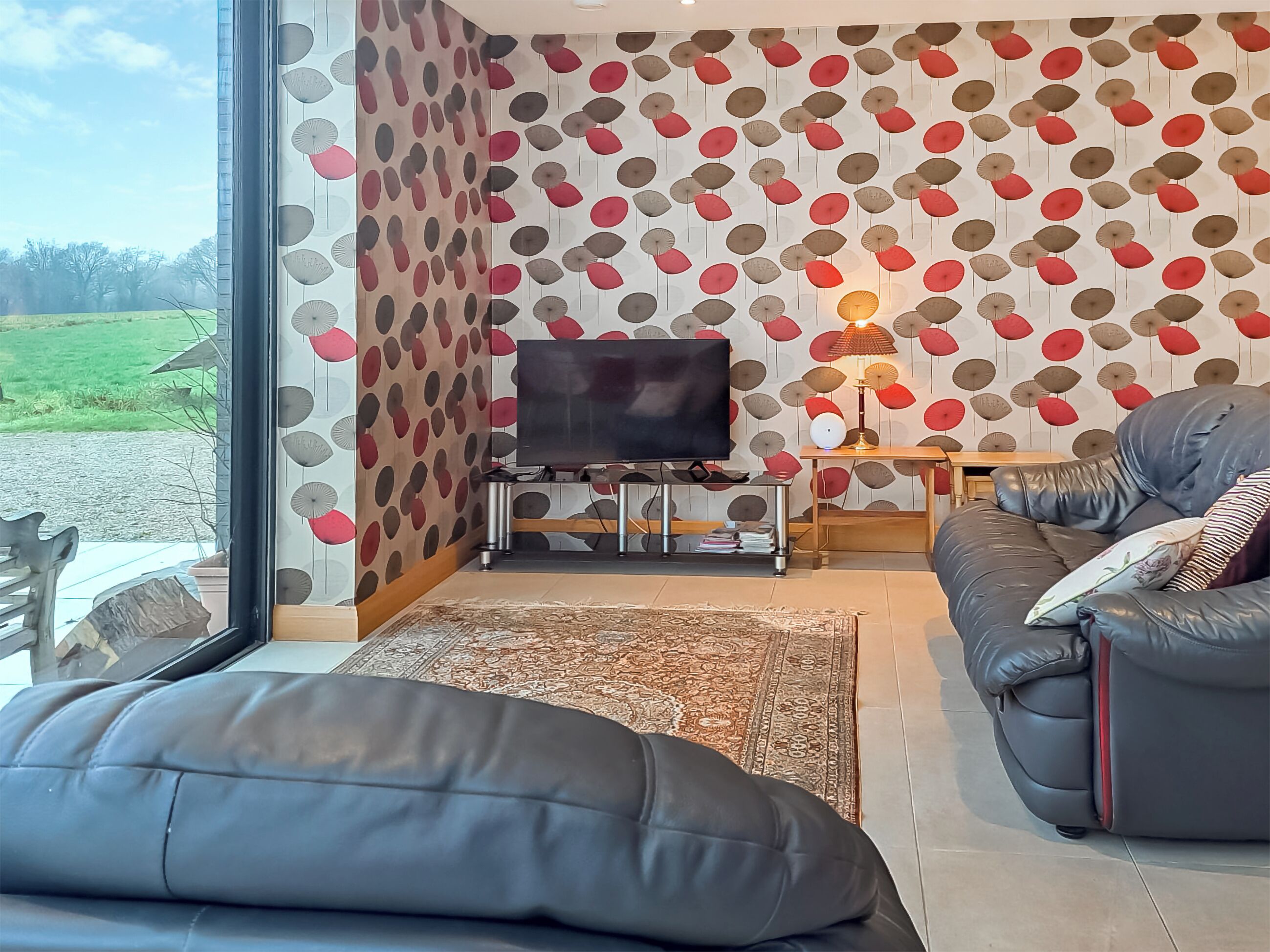 A living room with a TV, sofa, and a patterned wall.
