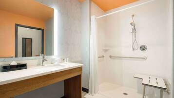 Une salle de bain moderne avec une douche, un meuble-lavabo avec un miroir et une petite table.