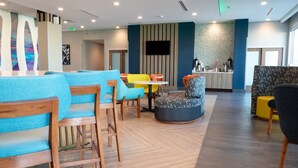 Ein stilvoller Lounge-Bereich mit Holzmöbeln und farbenfroher Sitzgelegenheiten, einem runden Tisch und einem Flachbildfernseher an der Wand.