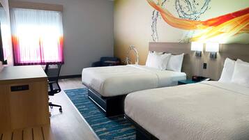 A hotel room with two beds, a desk, a chair, and a clock.