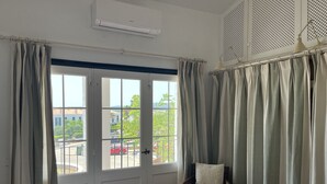 Ein Zimmer mit einem Bett, einem Sessel und einem fenster mit Vorhängen.