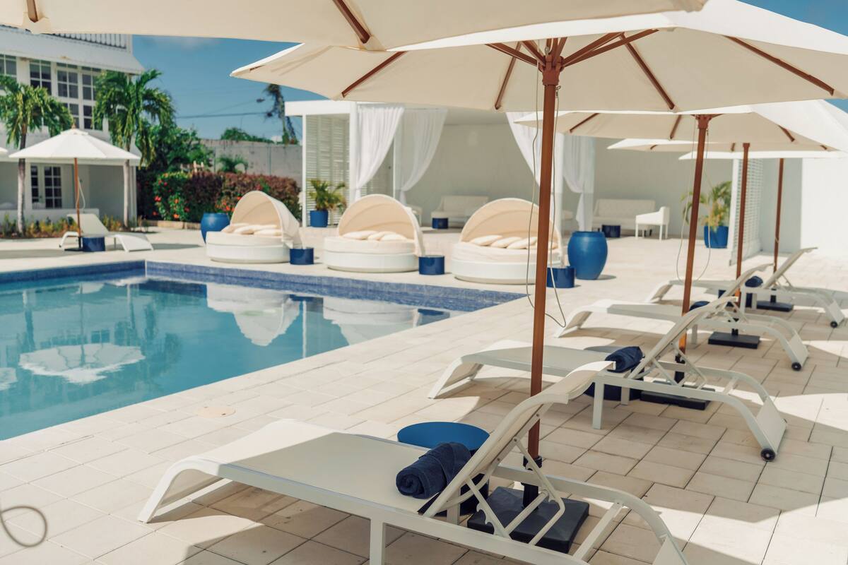 A poolside area with lounge chairs, umbrellas, and a swimming pool.