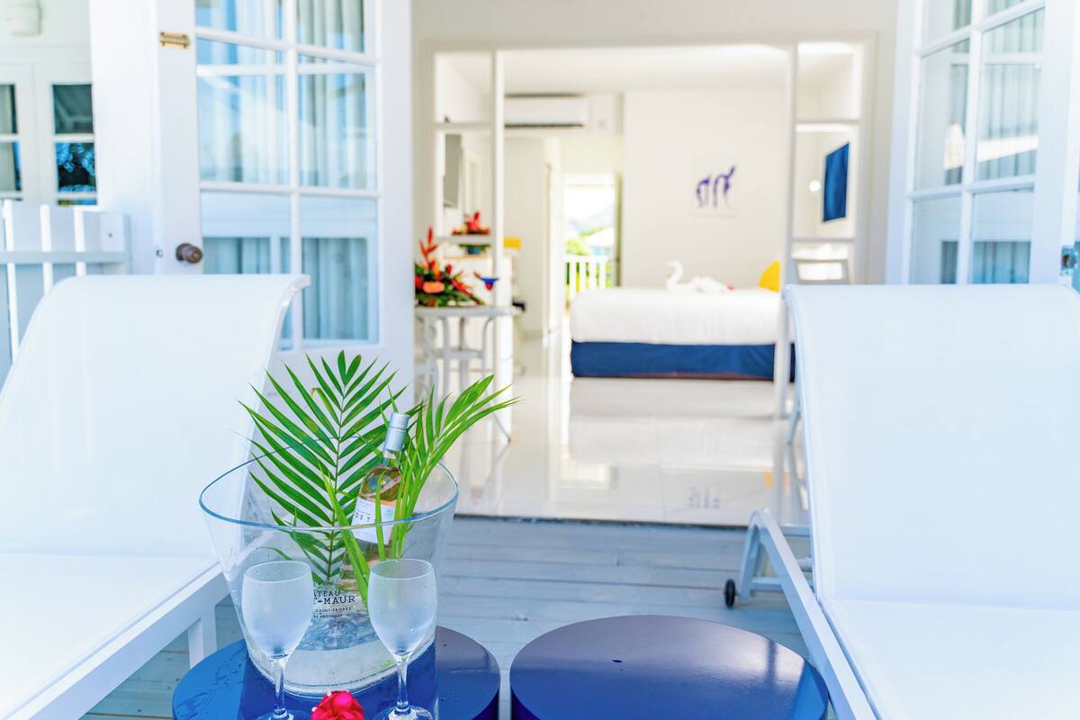 A room with a bed, a dining area, and a view of the sea.