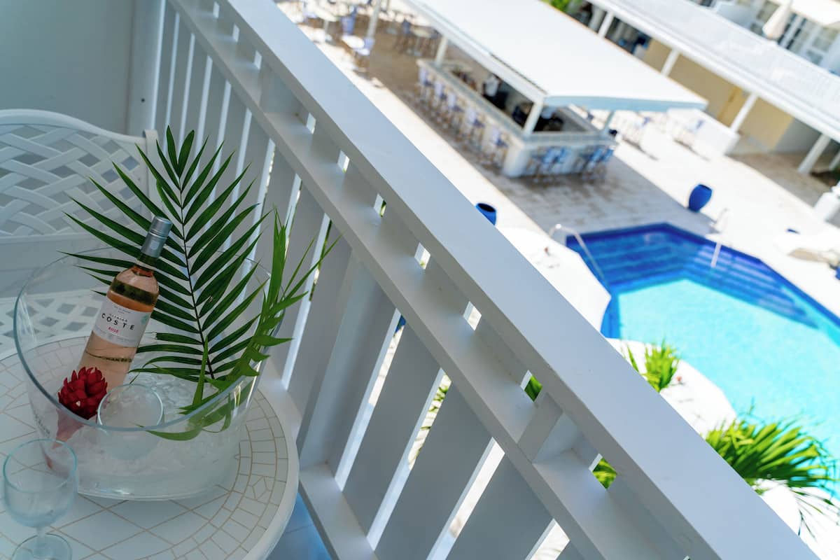 A balcony with a clear view of a swimming pool, a bar area, and a dining setup.
