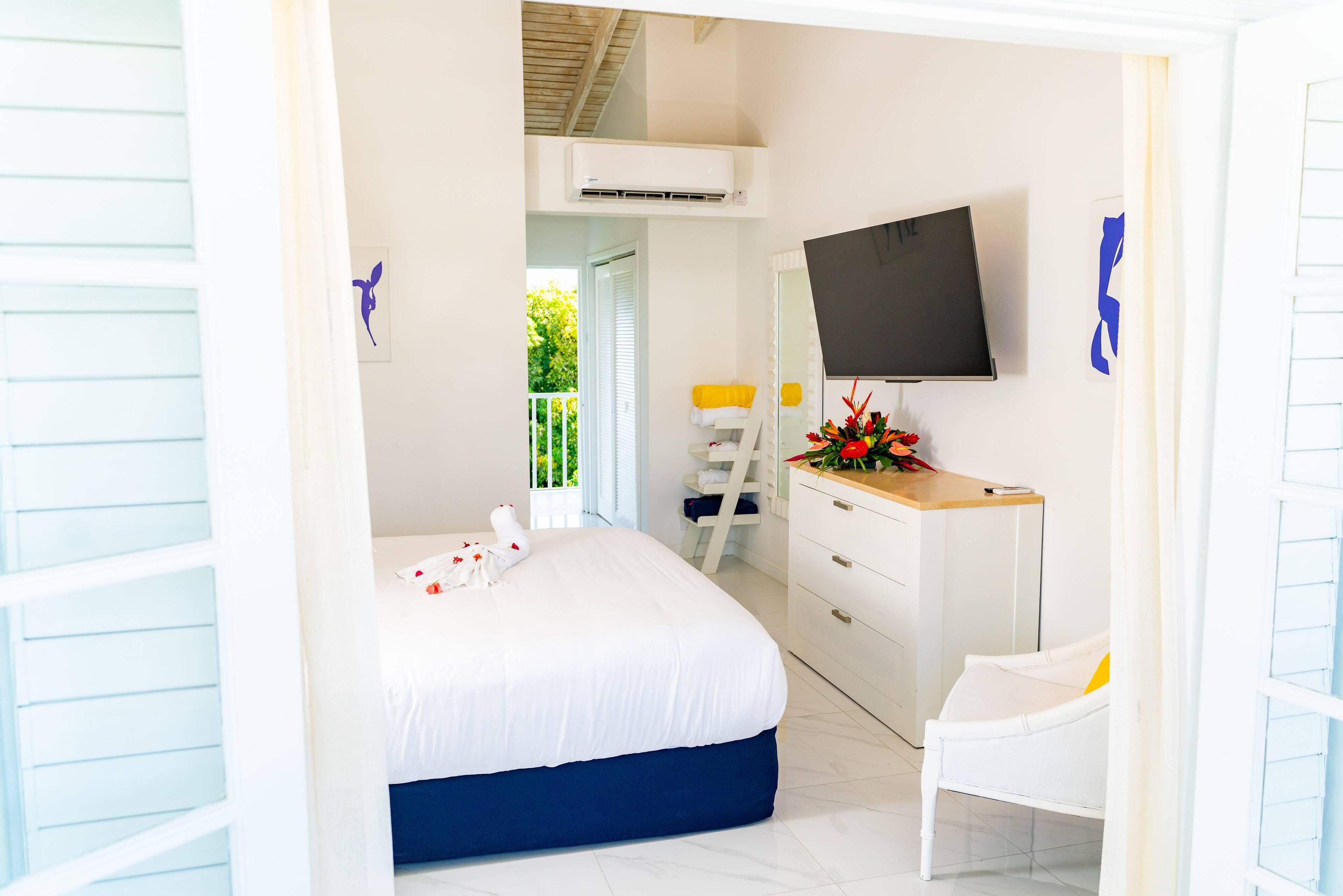 A bedroom with a bed, a dresser, a TV, and a chair.