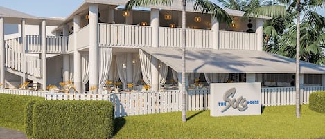 A multi-story hotel with a white exterior, balconies, and a sign reading "The Sea House".
