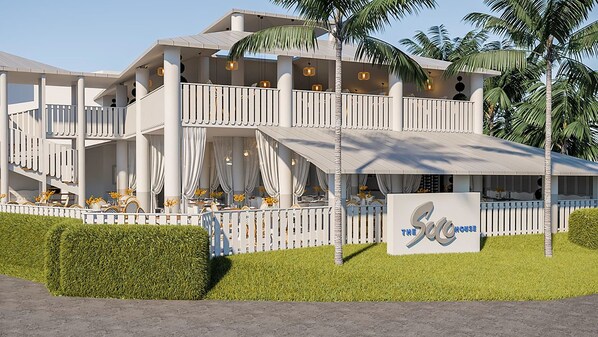 A multi-story hotel with a white exterior, balconies, and a sign reading "The Sea House".