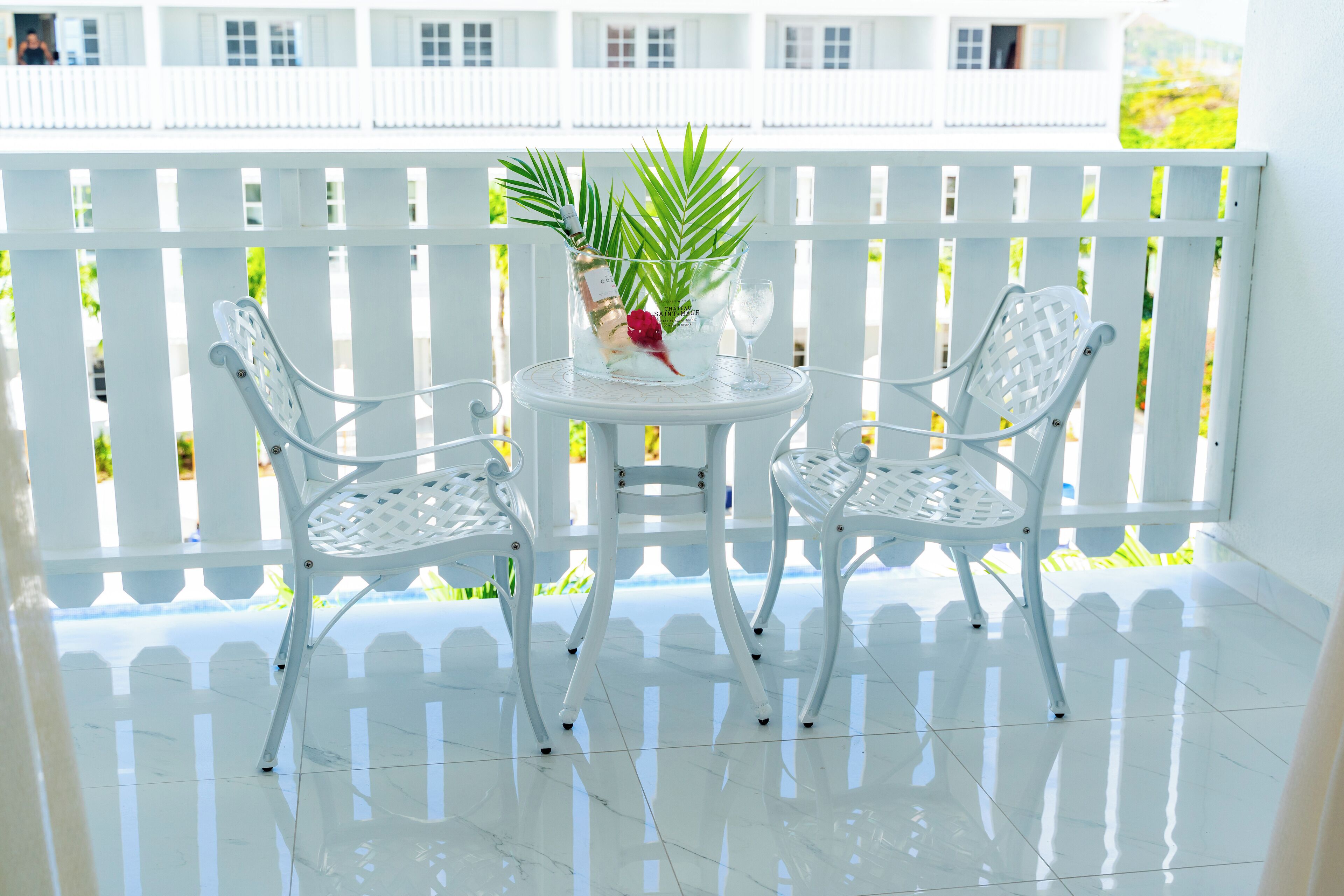 Un balcon avec deux chaises en métal blanches et une petite table ronde.