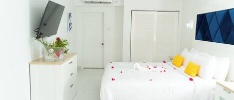 Un dormitorio moderno con cama, mesitas de noche, televisor y armario.