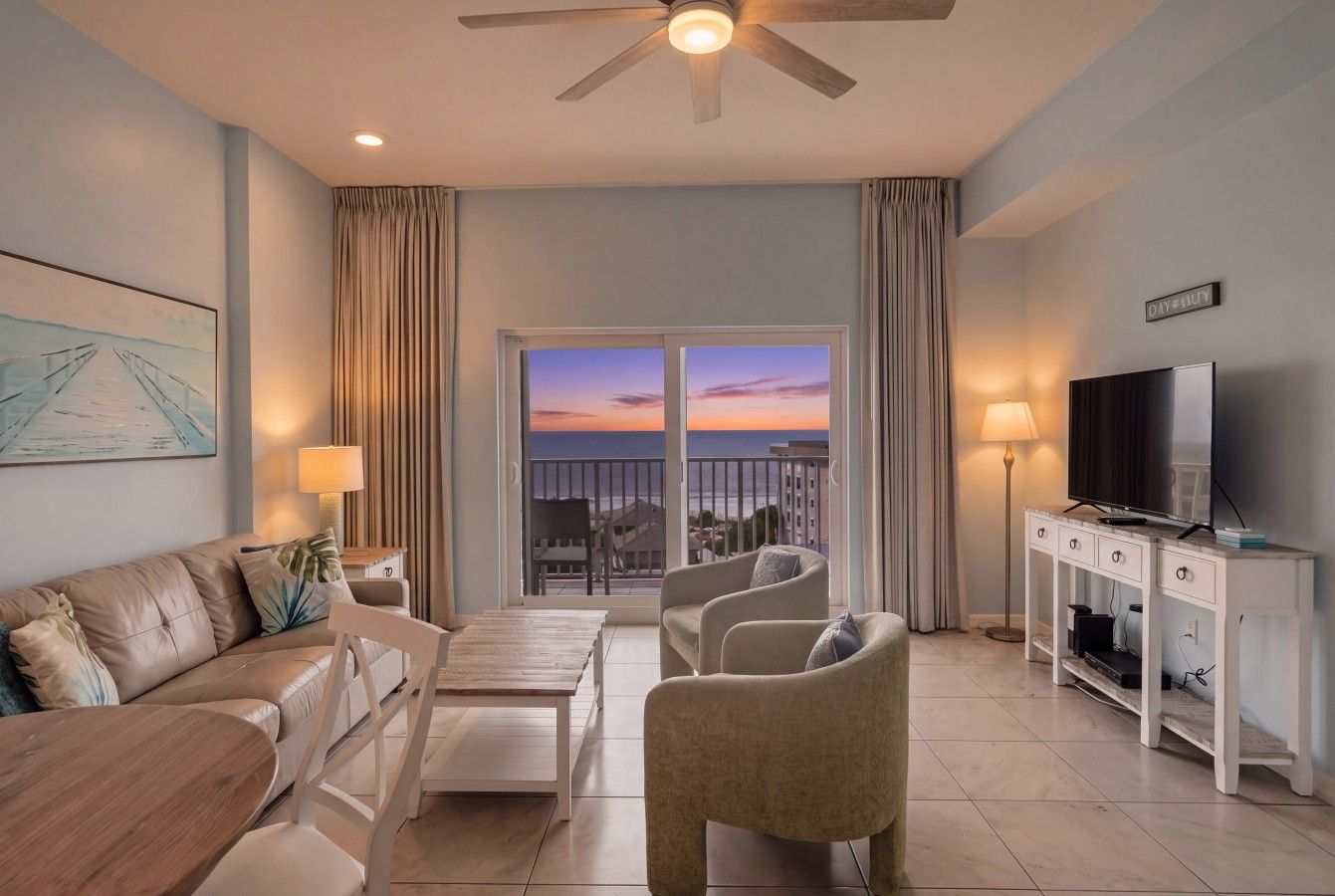 A modern living room with a sofa, chairs, a TV, and a balcony with a city view.