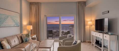 Una sala de estar moderna con un sofá, sillas, un televisor y un balcón con vista a la ciudad.