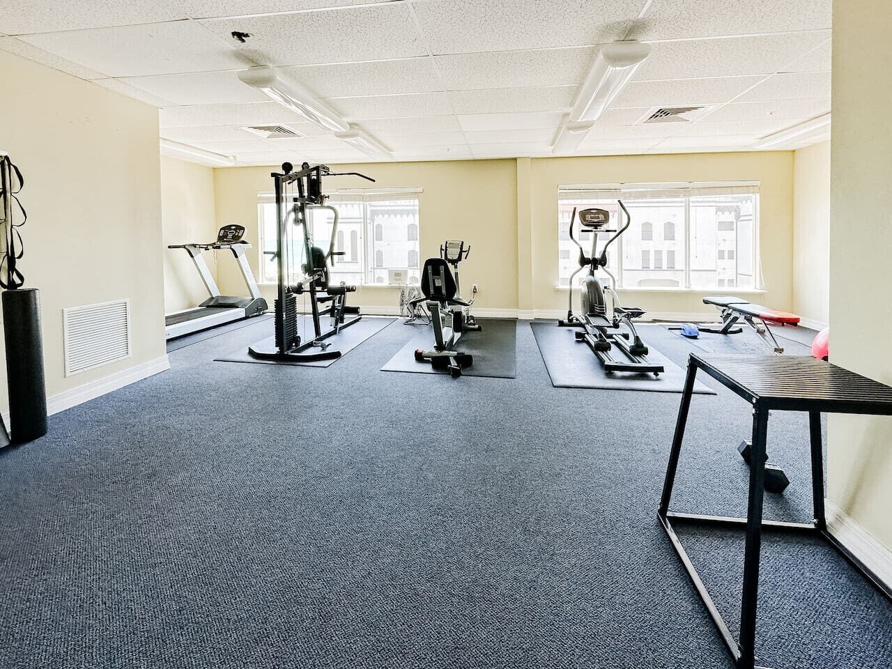 A gym with cardio machines, weight stations, and a small table.