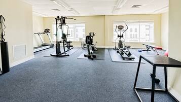 A gym with cardio machines, weight stations, and a small table.
