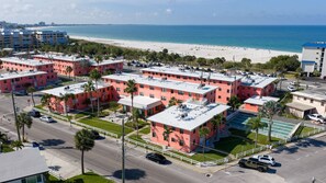 A coastal hotel with multiple pink buildings, a beach view, and a parking lot. - Paradise Awaits 250 Steps to Beach | Heated Pool (Saint Pete Beach)