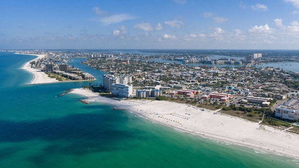 A coastal cityscape with a beach, high-rise buildings, and a marina. - Paradise Awaits 250 Steps to Beach | Heated Pool (Saint Pete Beach)