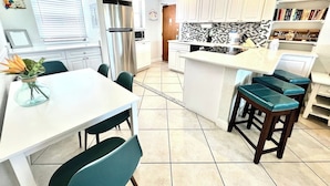 A modern kitchen with white cabinets, a central island, and bar stools. - Paradise Awaits 250 Steps to Beach | Heated Pool (Saint Pete Beach)